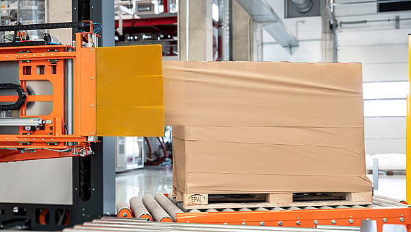 Automatische Stretchwickelmaschine, die Folie um eine palettierte Ladung in einem Lagerhaus wickelt.